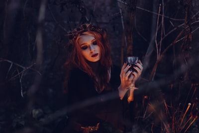 在森林里一个女孩手举酒杯的万圣节。
